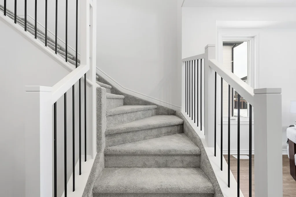 Carpeted staircase with white railings and black metal balusters.