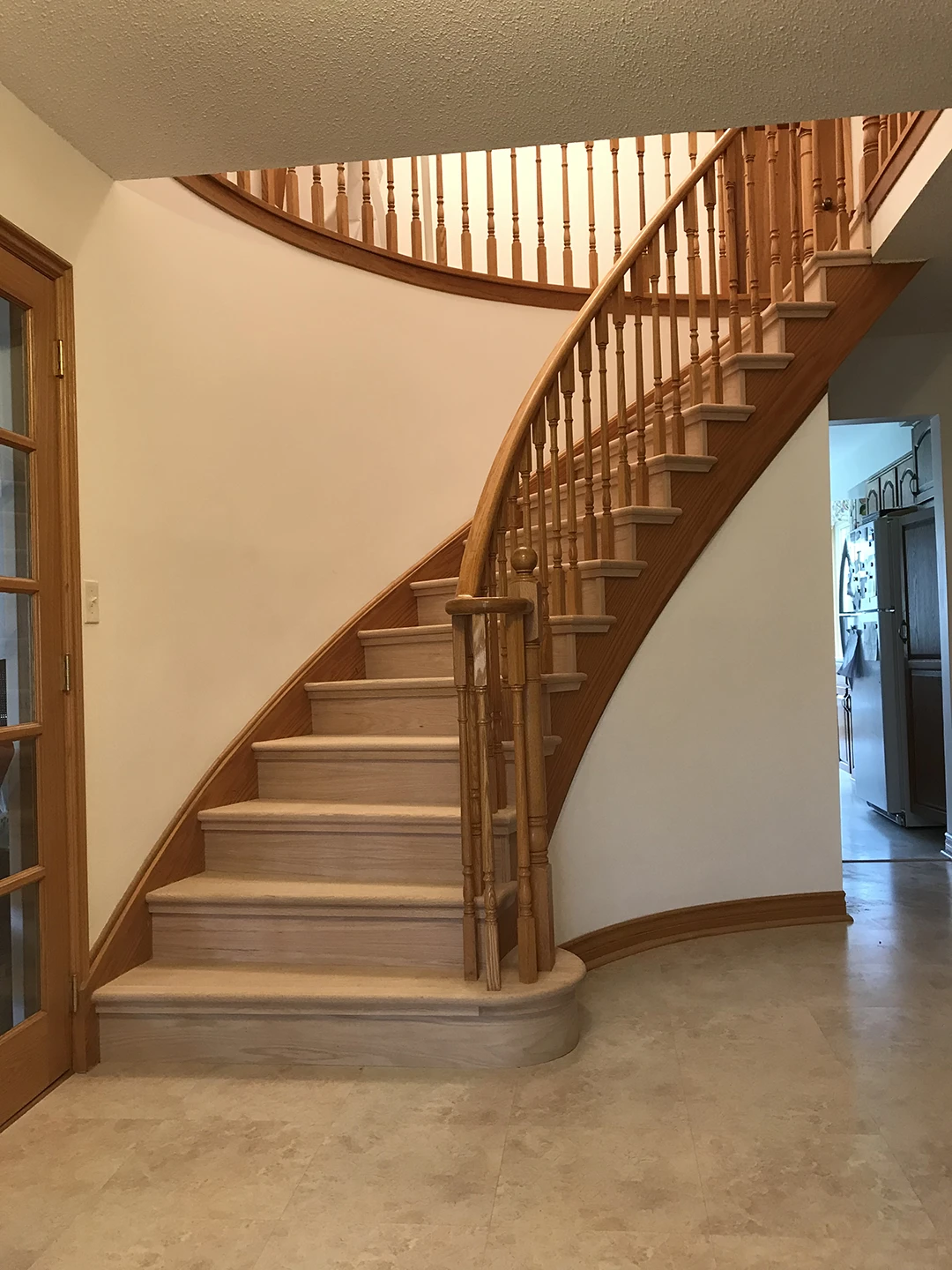 Renovated curved staircase with refinished wood railings.