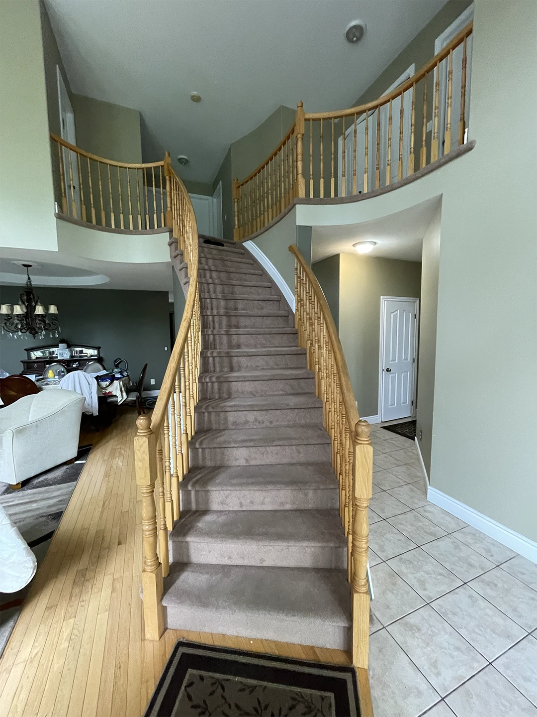 Renovated curved staircase with wood railings and carpet runner.